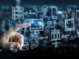 Verschiedene Piktogramme, die ein IT-Netzwerk symbolisieren, sind auf einer Ebene angeordnet – mit einer Hand im Hintergrund, die auf eines der Symbole deutet.