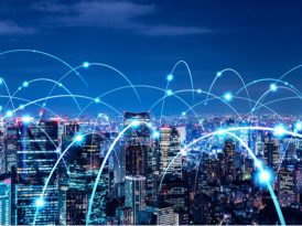 Nächtliche Skyline einer Großstadt, auf der die einzelnen Gebäude als Symbol für das LPWA-Roaming im IoT mit blauen Laserstrahlen verbunden sind