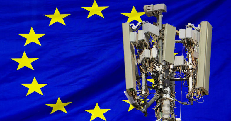 Der obere Teil des Sendemasts eines Telekommunikationsanbieters vor einer europäischen Flagge