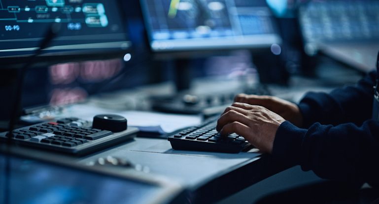 Close de um especialista de escritório profissional trabalhando no computador desktop na moderna sala de controle de monitoramento tecnológico com telas digitais. Gerente digitando no teclado e usando o mouse.