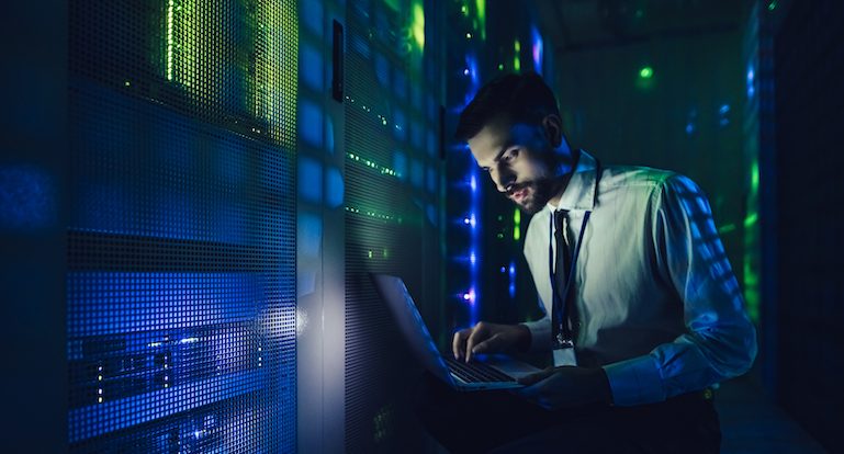 Technician examining server in big data center full of rack servers