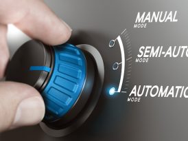 Hand turning a knob over grey background and selecting the automatic mode.